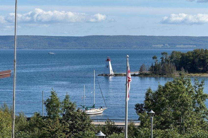 A lighthouse, a flag, a boat, and a forested shoreline. 4