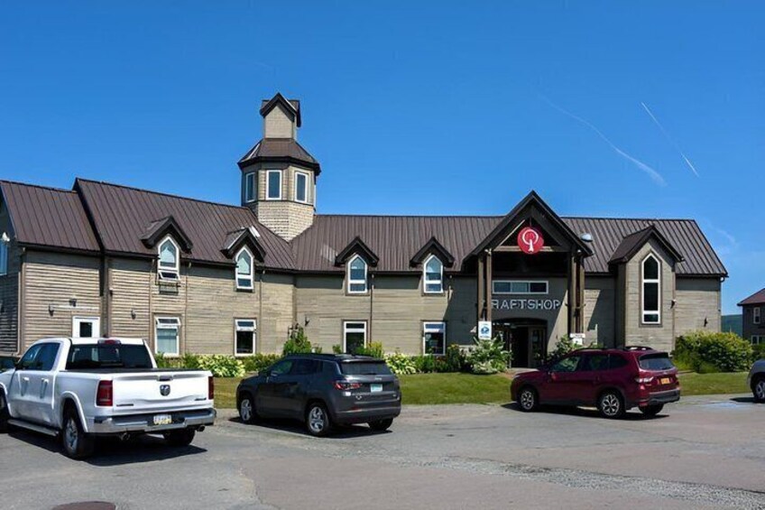 A building with a sign reading 'CRAFTSHOP' and parked vehicles in front. 5