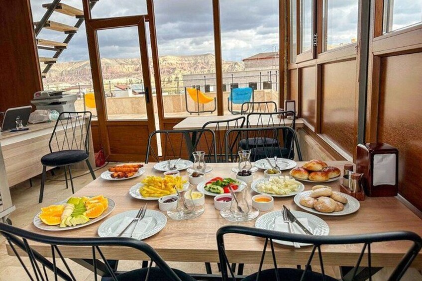 A dining table with various dishes, chairs, and a view of the outdoors. 3