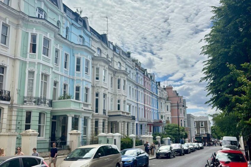 A row of colorful Victorian terraced houses with parked cars and pedestrians on the street. 3