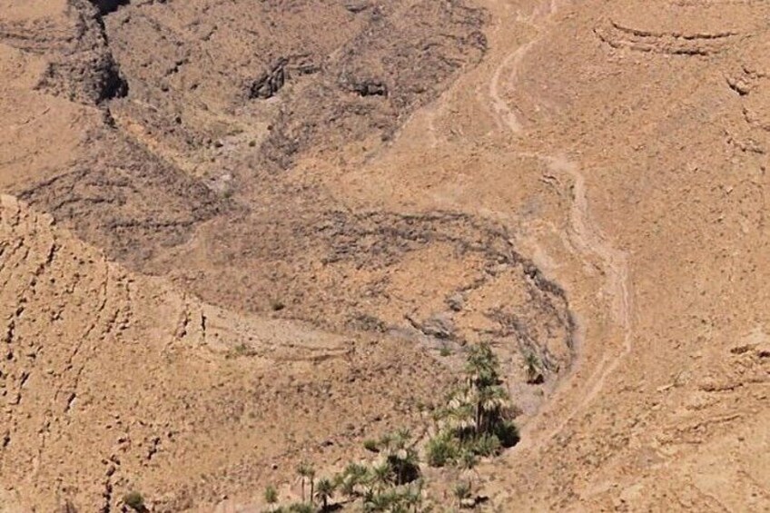 A dry, rocky landscape with a winding path and sparse vegetation. 5