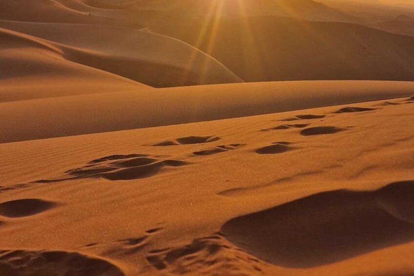 A desert landscape with sand dunes and footprints. 2