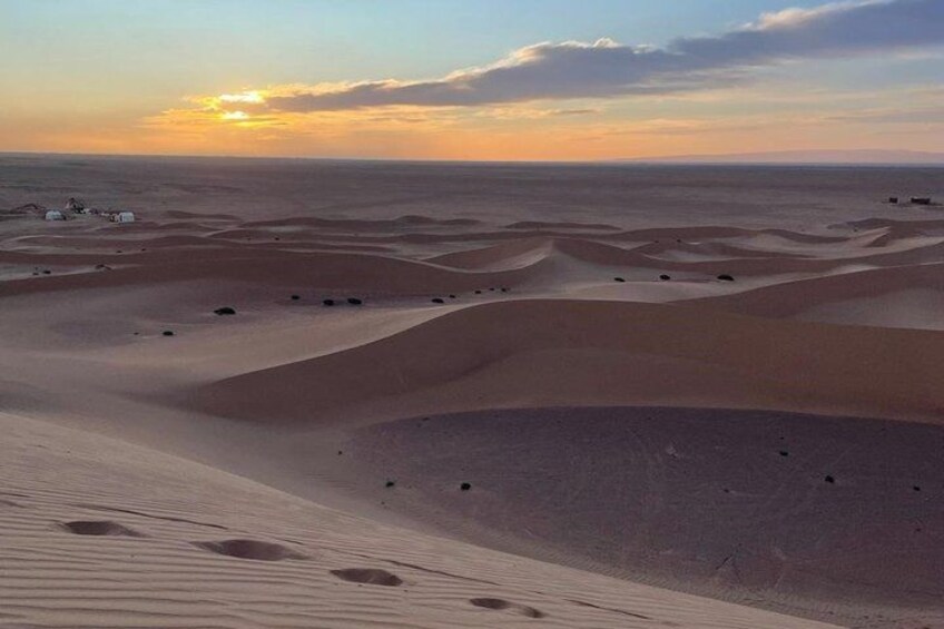 A desert landscape with sand dunes and a sunset in the background. 3