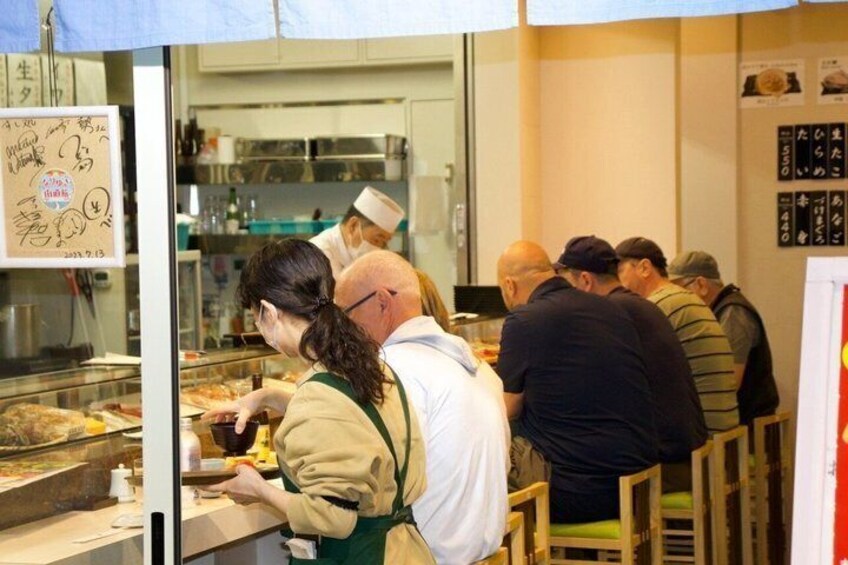 Un puesto de comida con gente pidiendo y comiendo. 4