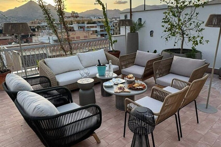 Een terras op het dak met tuinmeubilair, een eettafel en potplanten. 2