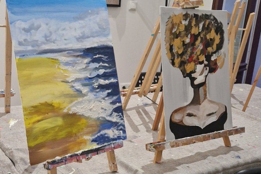 Dos cuadros sobre caballetes, uno representando un paisaje marino y el otro un retrato. 2