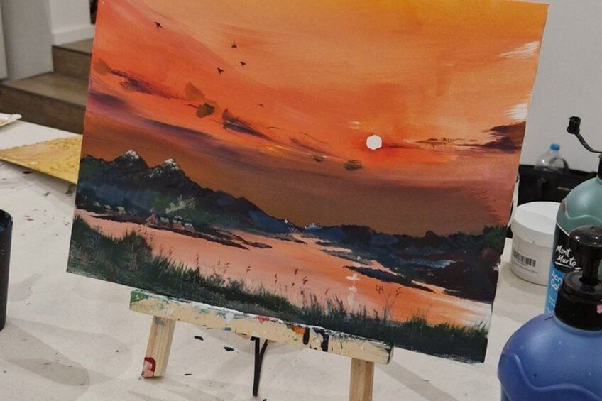 Una pintura de un paisaje al atardecer sobre un caballete. 4