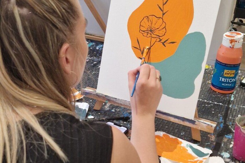Una persona pintando sobre un lienzo un diseño floral. 1