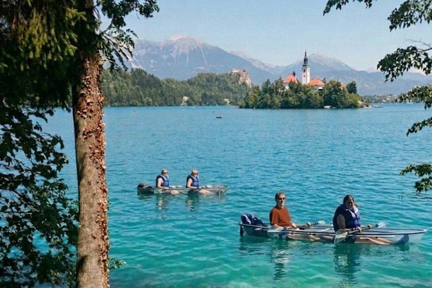 People rowing canoes on a lake with a church and mountains in the background. 2
