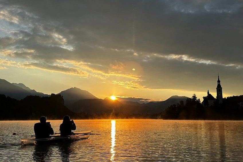 Atardecer sobre un lago con una iglesia y montañas al fondo. 5