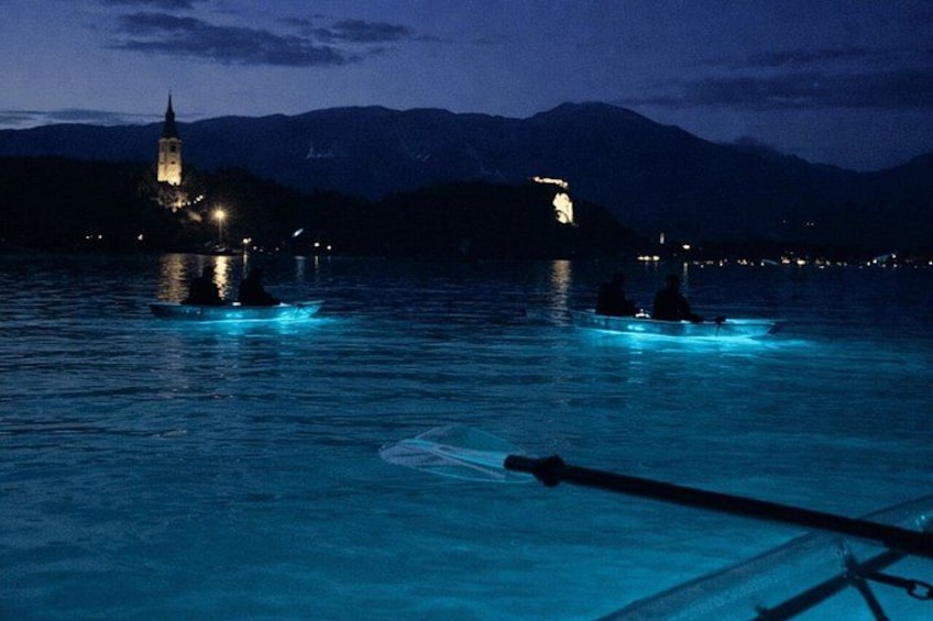 A nighttime lake with boats and a lit-up tower in the background. 5