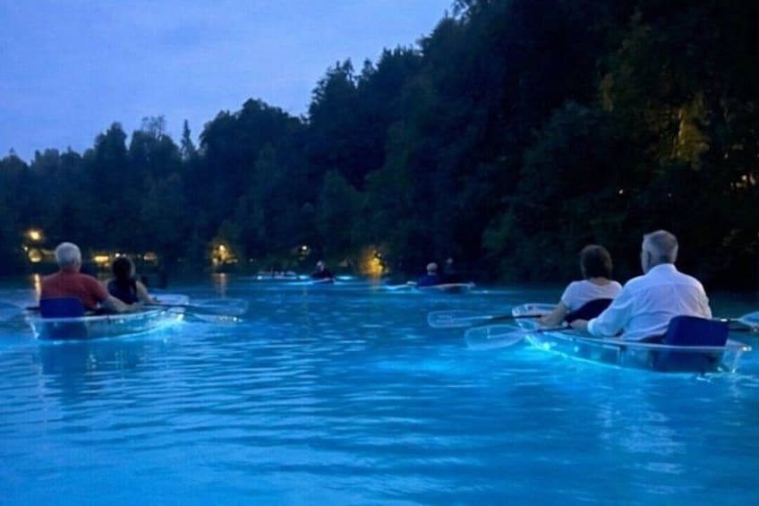 People in small boats on a calm body of water surrounded by trees. 4