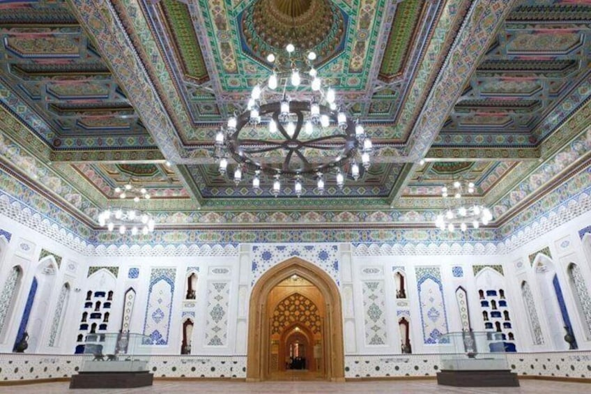 Un interno decorato con soffitto elaborato, un grande lampadario e un'ampia porta ad arco centrale. 5