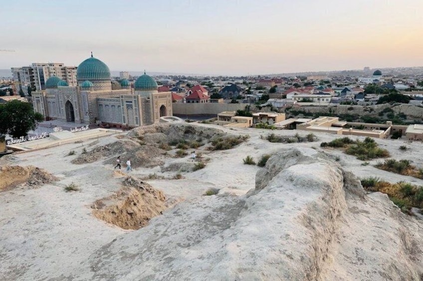Una grande moschea con numerose cupole, un paesaggio sabbioso e una città sullo sfondo. 4