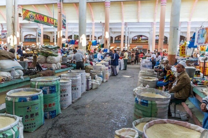Un vivace mercato al coperto con grandi sacchi di cereali e persone che fanno la spesa. 2
