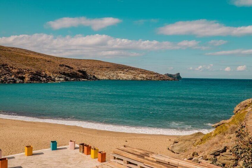 A beach with clear turquoise water, sandy shore, and rocky cliffs. 3