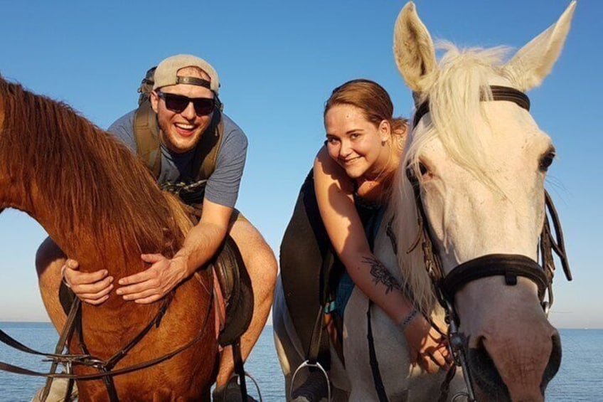 Dos personas montando a caballo en una playa con el océano al fondo. 4