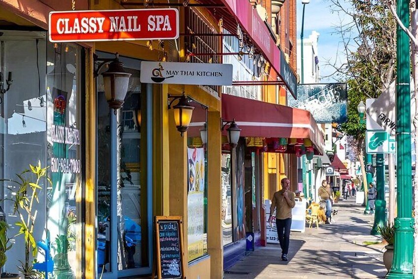 A street with storefronts, including a nail spa and a Thai kitchen. 2