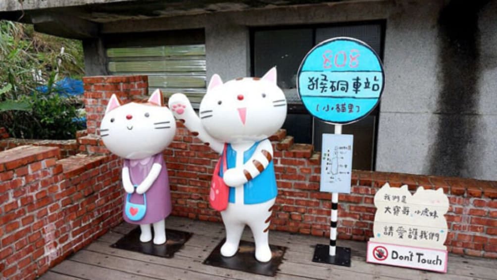 Two cat statues, a sign with the number 108, and a 'Don't Touch' sign. 4