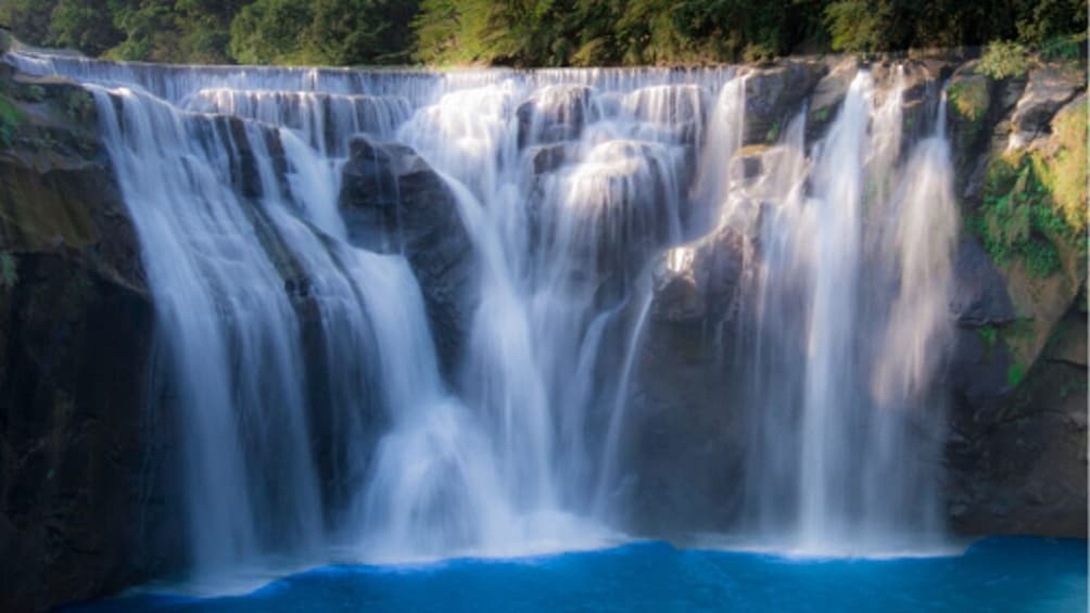 A waterfall cascading over a rocky cliff into a pool of water. 1