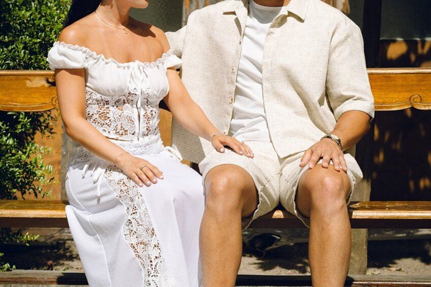 A couple sitting on a wooden bench outdoors. 5