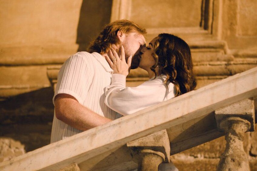 A couple kissing on a stone staircase. 1