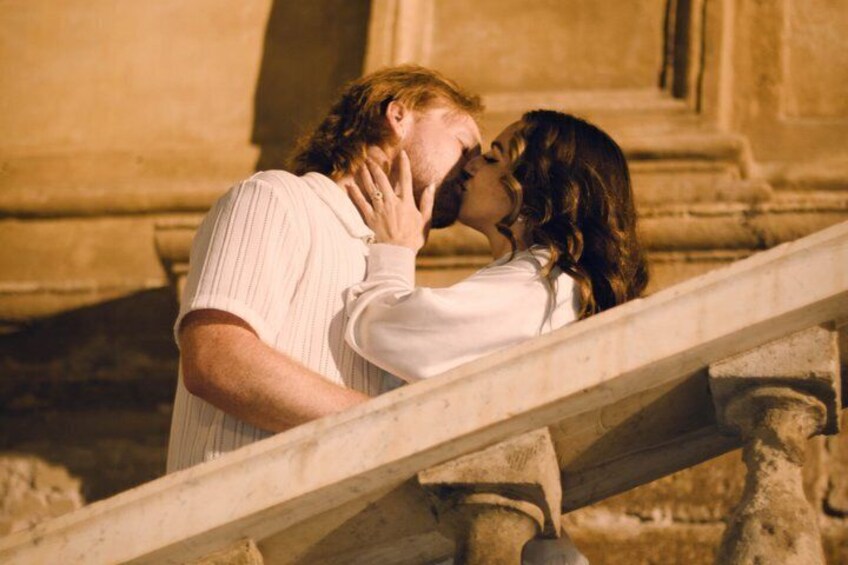 A couple kissing on a stone staircase. 1