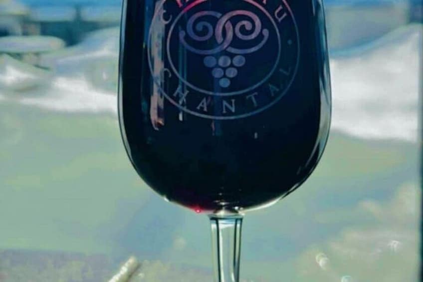 A wine glass with a logo, set against a blurred landscape background. 4