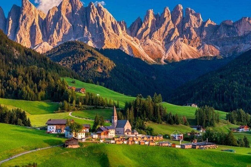 Un village niché dans une vallée, avec une église, entouré de champs verdoyants et de montagnes. 1