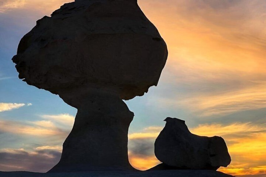 Eine Felsformation mit einem kleineren Felsen darauf, vor einem Sonnenuntergangshimmel. 5