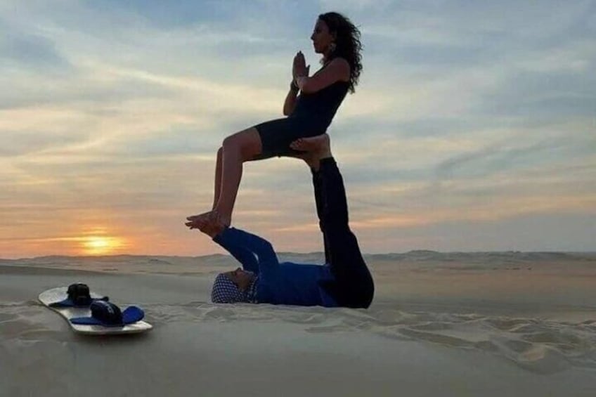 Eine Person vollführt eine akrobatische Leistung an einem sandigen Strand, im Hintergrund ein Sonnenuntergang. 3