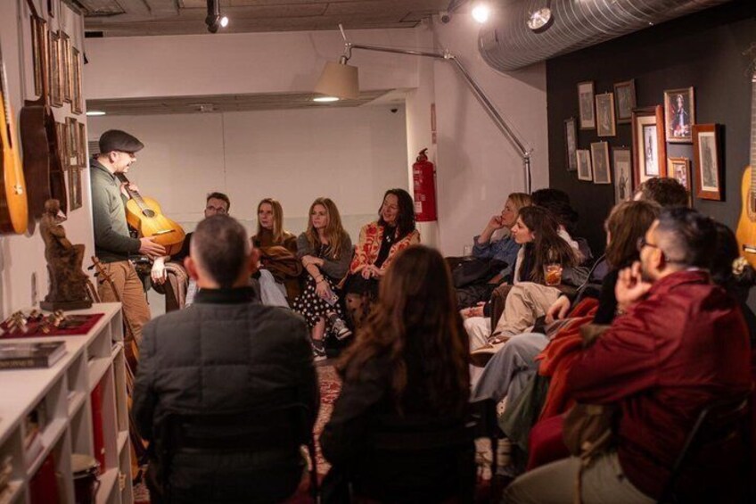 Un groupe de personnes est assis dans une pièce, et l’une d’entre elles joue de la guitare. 3