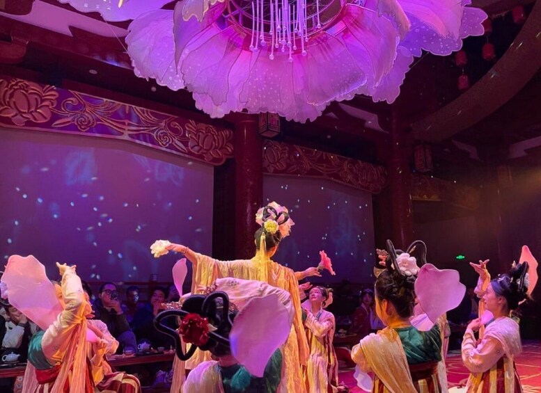 A traditional dance performance with performers in colorful costumes and a large decorative chandelier. 1