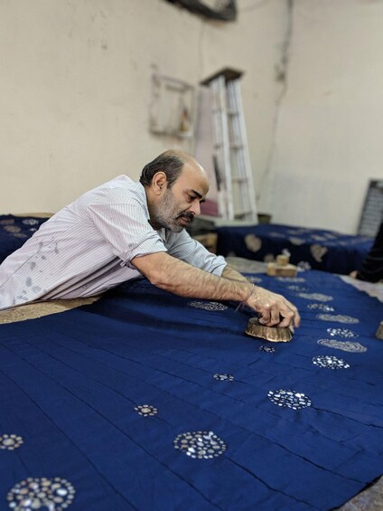 A person working on a blue fabric with circular patterns. 1