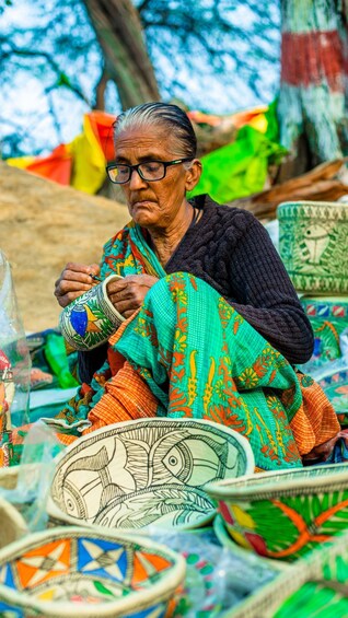 An elderly person crafting a colorful ceramic pot with intricate designs. 2