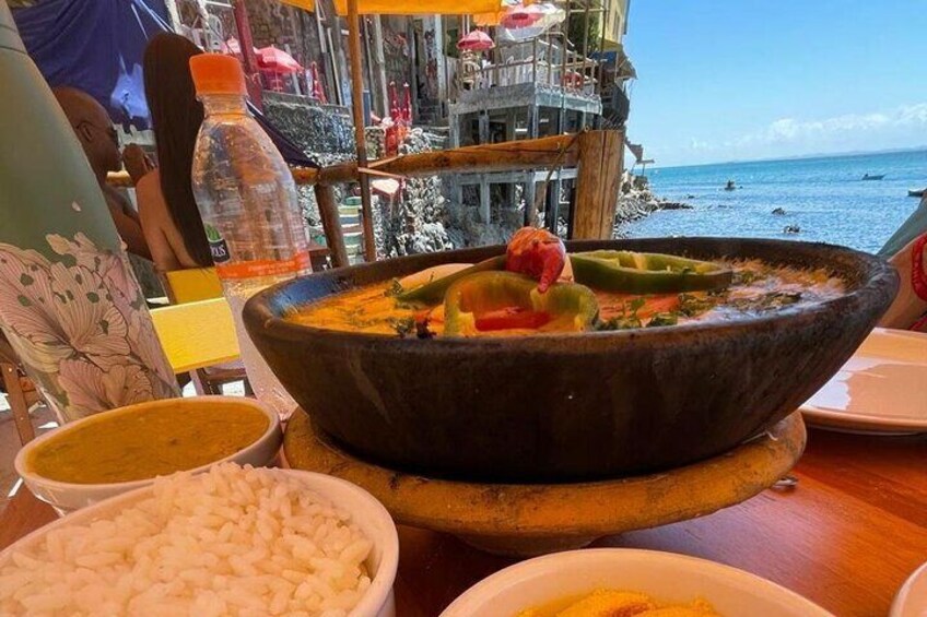A seafood dish with rice and vegetables on a wooden table, overlooking the sea. 1