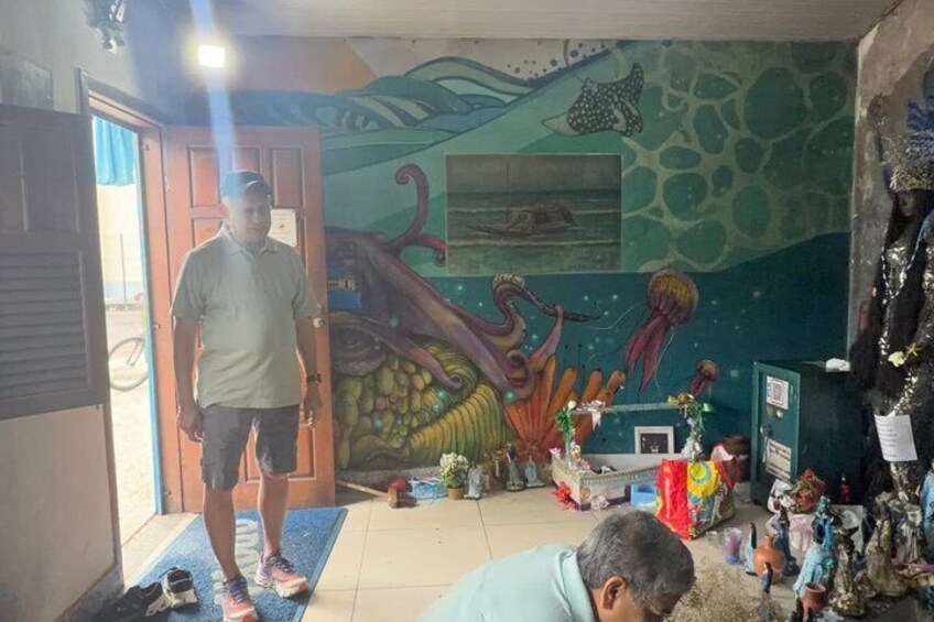 A room with a mural of sea creatures, a man standing, and various items on the floor. 4