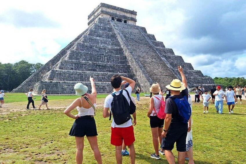 A large pyramid structure with tourists observing it. 4