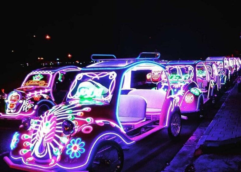 A row of brightly lit vehicles with intricate neon designs. 3