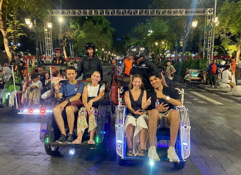 A nighttime outdoor event with people on illuminated carriages. 1