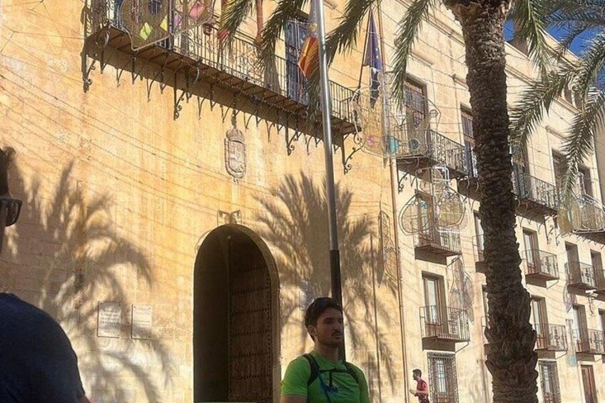 Un immeuble doté de balcons, de palmiers et de drapeaux. 2