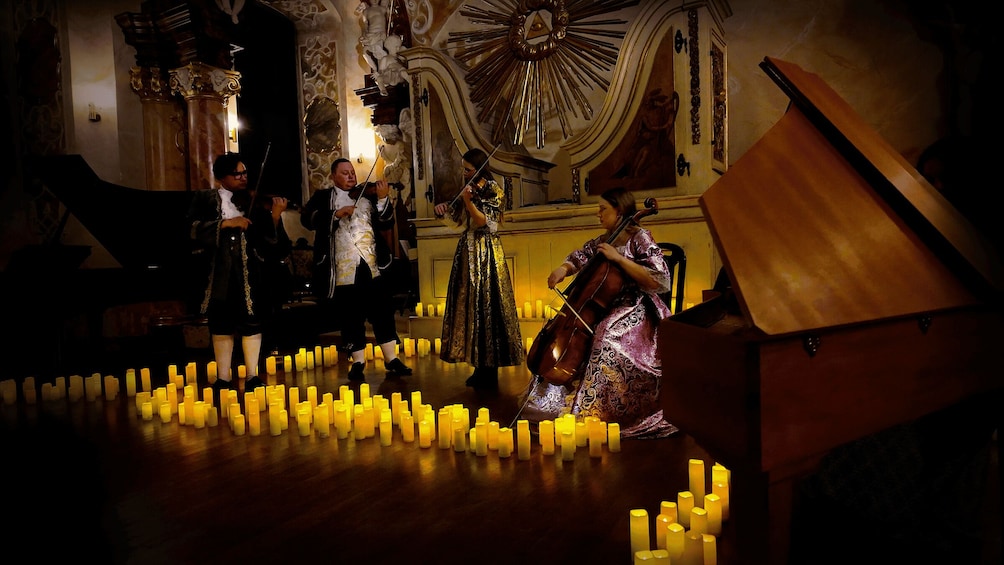 A classical music performance in a grand hall with candles on the floor. 2