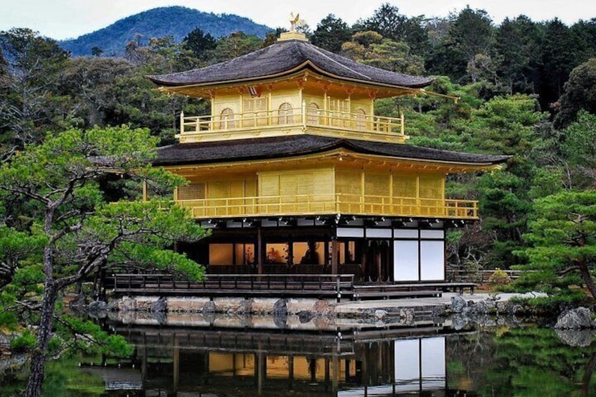 Un edificio japonés tradicional con tejado dorado, rodeado de exuberante vegetación y una masa de agua tranquila. 2