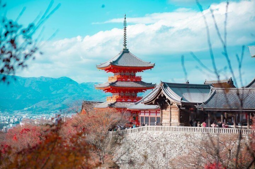 Un pagode japonés tradicional de varios niveles, rodeado de follaje otoñal y un telón de fondo montañoso. 1