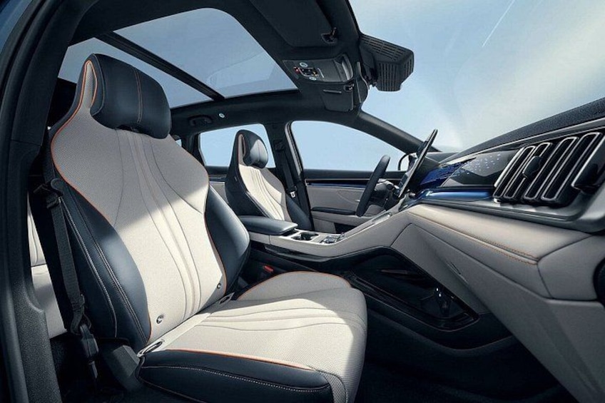 Een auto interieur met lederen stoelen, een stuurwiel en een schuifdak. 1