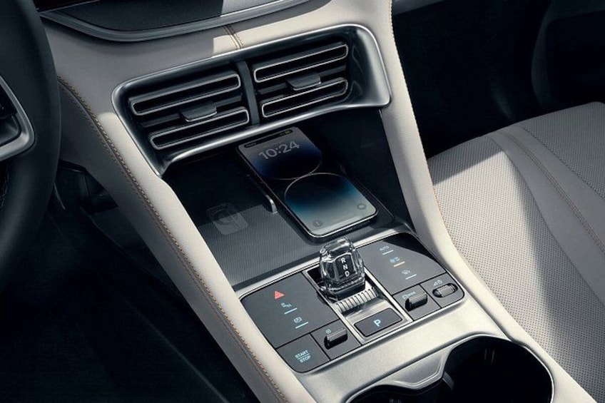 Het middenconsole van een auto met een digitaal scherm, versnellingspook en ventilatieroosters. 3