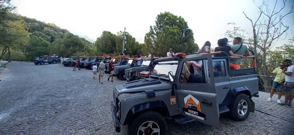 A safari vehicle with passengers, parked on a cobblestone path. 2