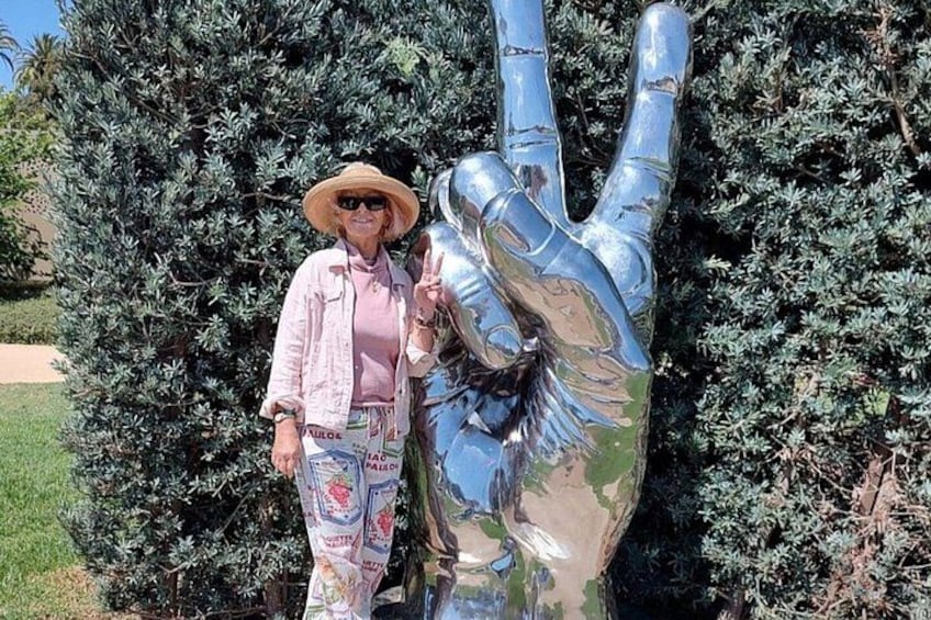 Une personne se tient à côté d’une grande sculpture métallique représentant une main. 2