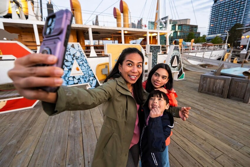 Eine Person macht ein Selfie mit einem Schiff im Hintergrund. 3