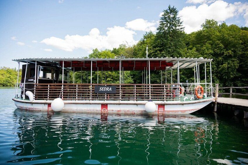 A boat named 'SEDRA' docked at a pier with a forested background. 3